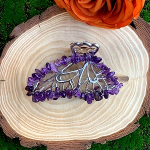 Detail of silver butterfly hair claw with purple crystal stones on wooden base
