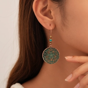 Vintage bronze bohemian mandala drop earrings with green enamel and beaded accents on model