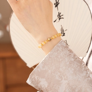 Close-up of citrine beaded bracelet with gold hollow sphere and crystal spacers on fan