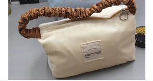 Detailed close-up of corduroy tote bag with brown ruched handle and eco-friendly label
