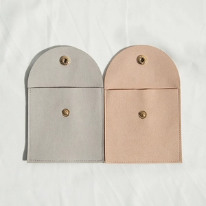 Detail of gray and beige microfiber jewelry pouches with snap buttons on white fabric