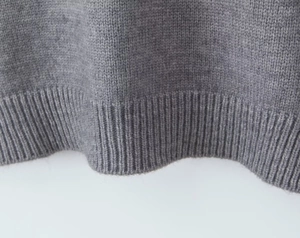 Gros plan détaillé du pull en maille grise avec ourlet côtelé large et texture douce