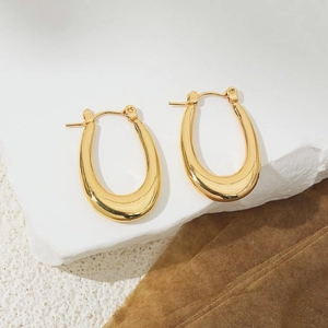 Macro view of minimalist 18K gold-plated U-shaped hoop earrings on white stone