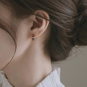Close-up of minimalist gold earrings with black gemstone worn on an earlobe