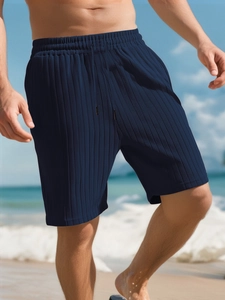 Detail of navy blue pleated shorts featuring an elastic drawstring waistband and textured fabric