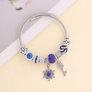 Silver charm bracelet with blue rhinestones, snowflake and key pendants on a pale background