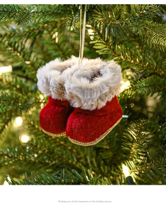 Close-up of red felt Christmas boot ornaments with faux fur trim on a lit Xmas tree