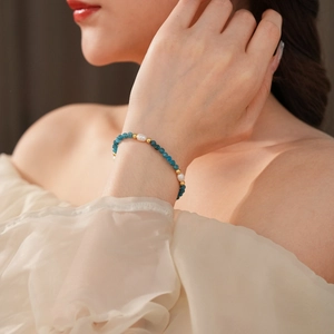 Detail of beaded bracelet with blue stones and freshwater pearls worn by a model