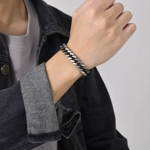 Detailed view of silver stainless steel Cuban link bracelet worn by a male model
