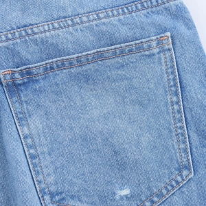 Detail of light blue denim jeans showing the back pocket with contrast stitching