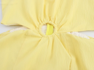 Dettaglio del tessuto giallo con trama stropicciata, design traforato e cerniera centrale