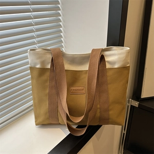 Minimalist canvas tote bag with contrast stitching and brown handles for daily use