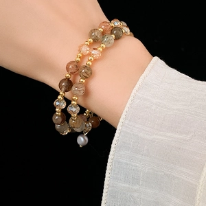 Macro detail of a double-layered beaded bracelet with rutile quartz and a grey pearl
