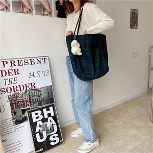 Model showing large plaid canvas tote bag in navy and green with sheep charm