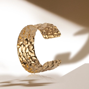 Minimalist wide gold cuff bracelet with hammered texture and soft shadow reflection