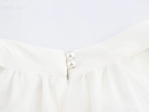 Details des eleganten weißen Stehkragens mit Perlenknöpfen und plissiertem Chiffon