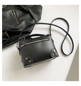 Top view of a black studded crossbody bag with silver hardware on a clean white surface