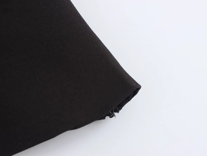 Gros plan sur la texture du tissu noir et les coutures fines du haut à nœud papillon