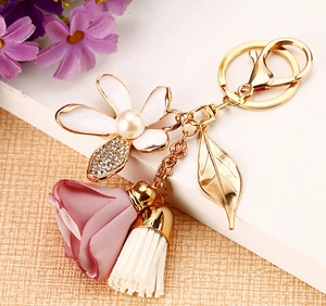 Detailed close-up of a floral keychain with silk rose, daisy charm, and white tassel