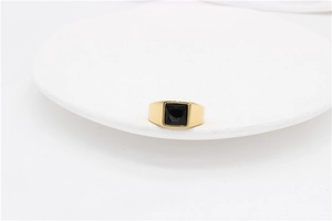 Macro shot of minimalist gold titanium ring featuring a large square black gemstone