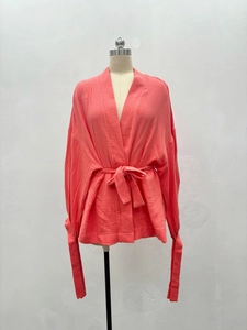 Detail of coral orange long sleeve kimono wrap top with unique crinkle texture fabric