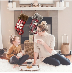 Plaid Christmas stockings for pets with faux fur trim hanging by a cozy fireplace