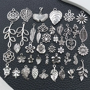 Détail de breloques botaniques en alliage argenté avec motifs de feuilles et de fleurs