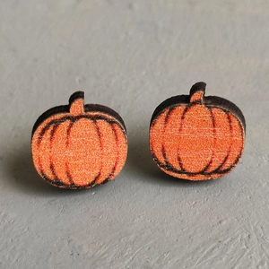 Macro view of handmade wooden pumpkin earrings with orange finish and black outlines