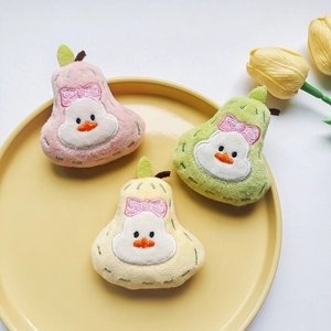 Detailed view of colorful plush pear brooches in pink, yellow and green on a tray