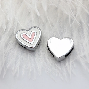 Macro shot of pink and white enamel heart bead for 8mm wristbands on soft white feathers