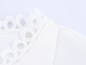 Close-up of white woven fabric with delicate hollow lace trim on elegant women blouse