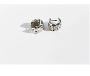 Macro detail of silver square hoop earrings with molten lava texture and metallic finish