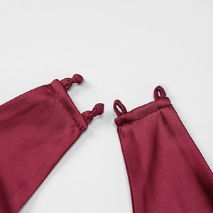 Detailed view of dark wine red satin fabric with delicate knot and strap craftsmanship