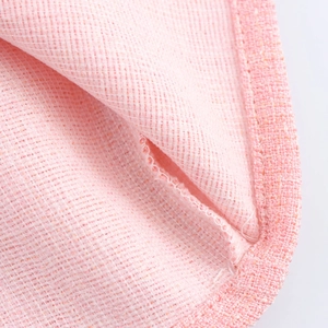 Pink tweed dress fabric detail showing delicate grid texture and stitched hemline
