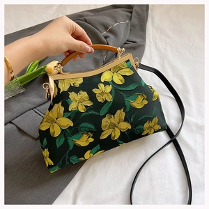 Close-up of vintage dark green qipao handbag with yellow floral embroidery and wooden handle