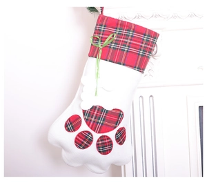 Detail of Christmas cat paw stocking with red plaid cuff and bone charm on white fireplace