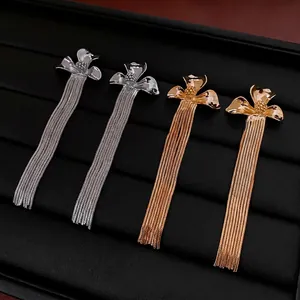 Elegant gold and silver flower tassel drop earrings on black velvet display tray