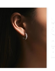Détail de boucles d'oreilles en forme de C en argent avec des pierres de moissanite brillantes