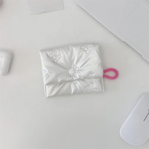 Detailed view of quilted white bow coin purse with pink lanyard for earbuds storage