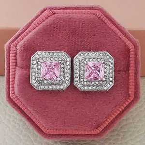 Macro detail of square pink zircon stud earrings with double halo in a velvet box