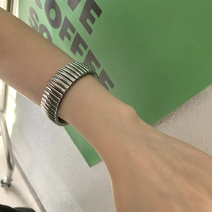 Détail d'un bracelet extensible argenté avec texture striée verticale porté au poignet