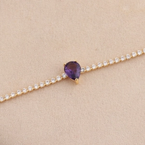 Close-up van een gouden tennisarmband met een peergeslepen amethist en kleine diamanten