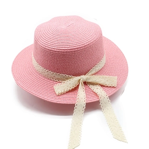 Detail of pink straw flat top hat featuring delicate beige lace band and a sweet bow