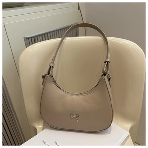 Detail of beige faux leather shoulder bag with a small silver bow and zipper closure