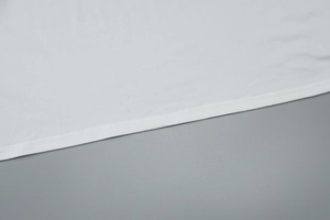 Macro detail of the white dress hem showing high-quality stitching and fabric texture