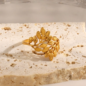 Vintage golden leaf branch ring with intricate organic textures on a white stone base