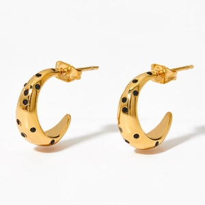 Detail of C-shaped gold hoop earrings featuring small inlaid black zircon stones on white