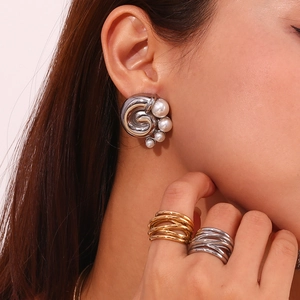 Macro detail of silver whirlpool earrings featuring white pearls and twisted metal texture