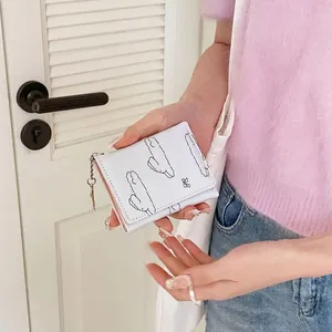 White minimalist rabbit bow wallet with cloud print held by hand on wood background