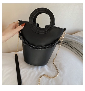 Detail of black PU leather bucket bag featuring round cutout handle and resin chain